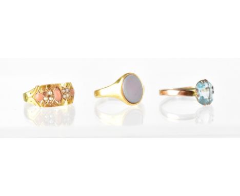 Three gold fashion rings including a 15ct gold pink coral and seed pearl, size K, a 9ct blue stone ring, size N and a gold si