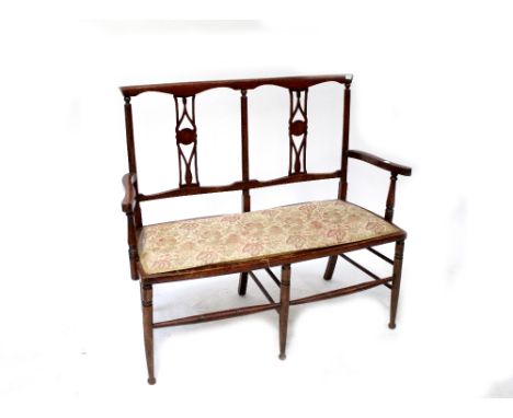 An early 20th century stained pine two-seater bench with shaped splat above upholstered seat, raised on turned stretchered su