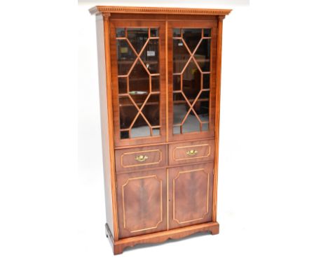A reproduction bookcase with dentil moulded cornice above pair of astragal glazed doors flanked by Corinthian columns above t