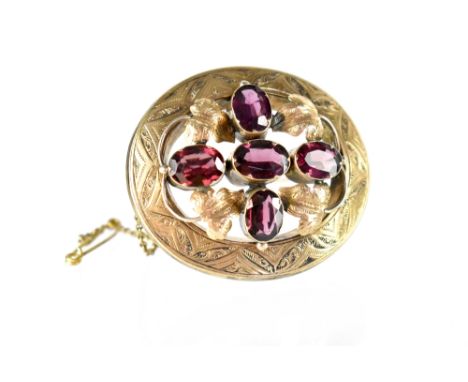 A yellow metal oval brooch with Art Nouveau and leaf decoration set with five amethysts, length 4.5cm.