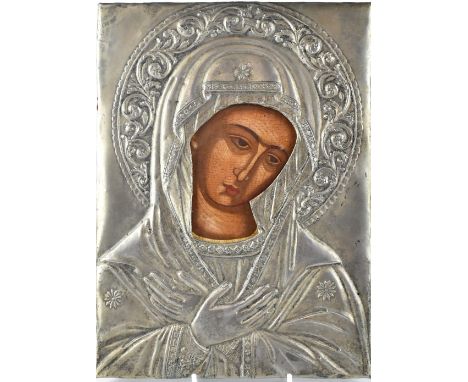 An antique Russian painted icon depicting the portrait of The Virgin Mary on wood panel protected by a white metal oklad form