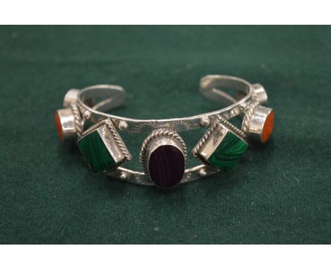 A heavy silver bangle set with coloured stones.
