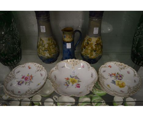 A set of four Royal Nymphenburg porcelain plates and a bowl painted with flowers.