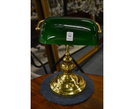 A brass desk lamp with green glass shade.