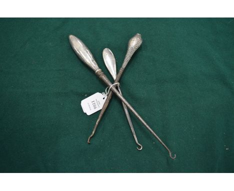 Three silver handled button hooks.
