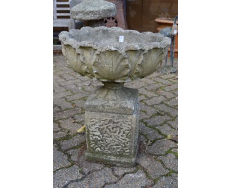 A reconstituted stone pedestal planter.
