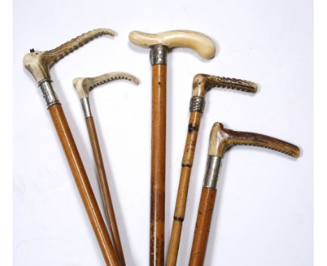 A Victorian ivory handled walking stick and four riding crops with bone handles