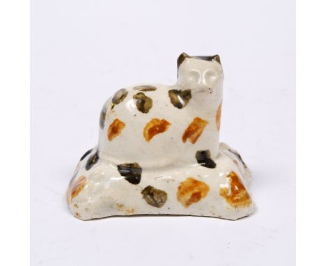 A sponge decorated Prattware cat circa 1800, modelled seated on a square base, 8cm x 5cm, 6.25cm high Provenance:  Roger de V