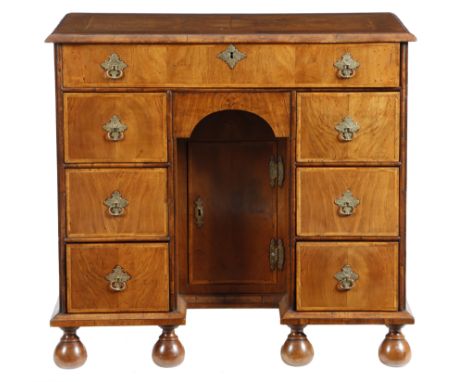 A walnut kneehole desk in William &amp; Mary style, cross and feather banded, the quarter veneered top above an arrangement o