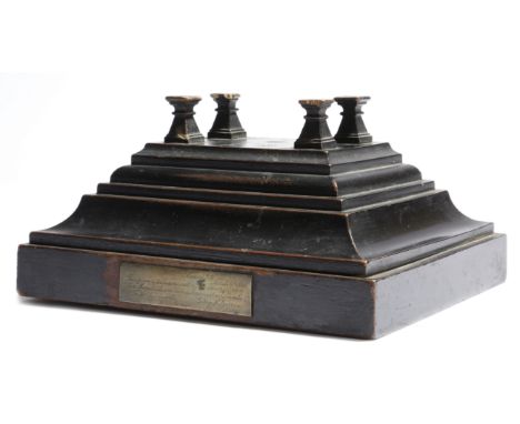 An ebonised wood stand, of stepped form, the top with four column supports, mounted with a brass plaque, engraved 'Cowes I. W