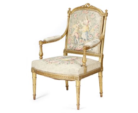A French giltwood fauteuil in Louis XVI style, with a padded back, seat and armrests, covered with tapestry with romantic sce