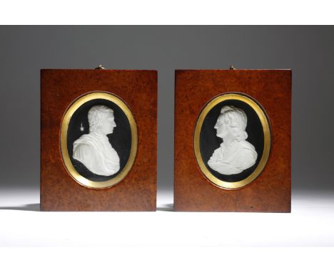 A pair of early 19th century plaster portrait relief busts of gentlemen, with an ebonised ground, in gilt slips and amboyna f