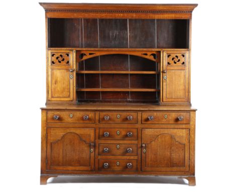 An early Victorian North Wales oak bread and cheese dresser, the moulded dentil cornice above a pair of cupboards with pierce