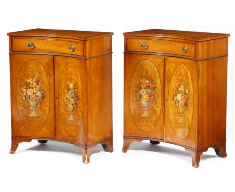 A pair of Edwardian Sheraton revival satinwood concave side cabinets, each with a frieze drawer above a pair of cupboard door