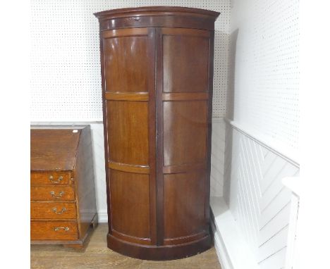 A late 19thC mahogany bow-front Wardrobe, the panelled doors opening to an interior with single shelf and rail, raised on pli