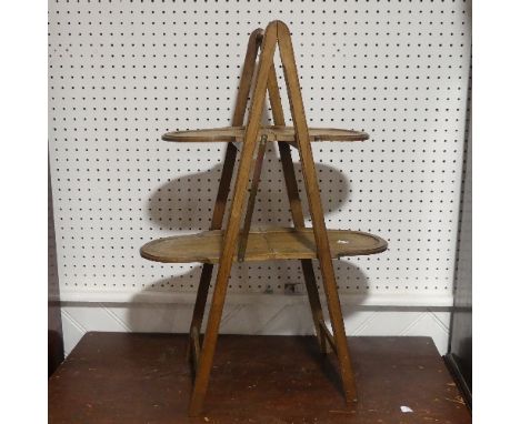 A vintage folding Cake Stand, with two tiers and brass carrying handle, fading and watermarks, 78cm High. 