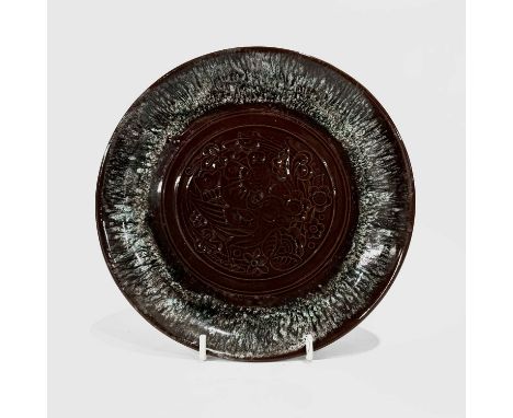Christopher Dresser for Linthorpe, an art pottery plate, dust pressed in relief with a bird and foliage, within marbled green