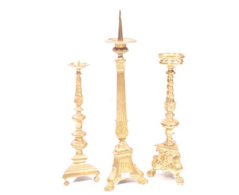 A collection of three 19th century brass church alter tripod pillar candlesticks. Ecclesiastical gothic manner with spike / d