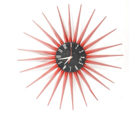 A contemporary red painted sunburst wall clock. Enamel red rays with circular ebonised face with Arabic number chapter ring a