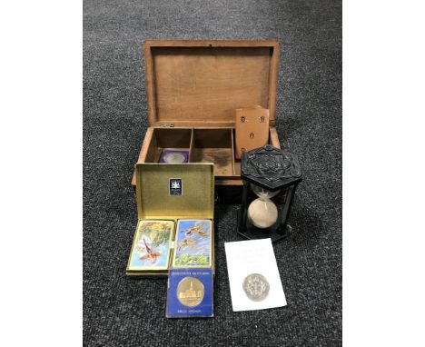 A carved Indian trinket box with key, commemorative crowns, hour glass on stand, two sets of playing cards 