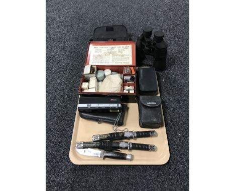 A tray consisting of cased binoculars, cameras, two miniature knives in the form of samurai swords, a hunting knife, together