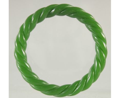 A CARVED GREEN JADE TWIST BANGLE. 3ins diameter.