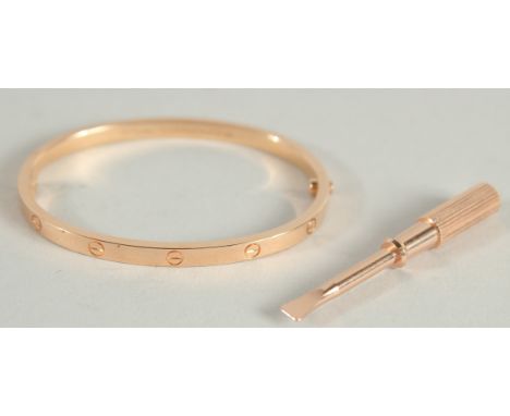 A CARTIER .750 GOLD LOVE BANGLE AND KEY in a fitted red Cartier pouch.