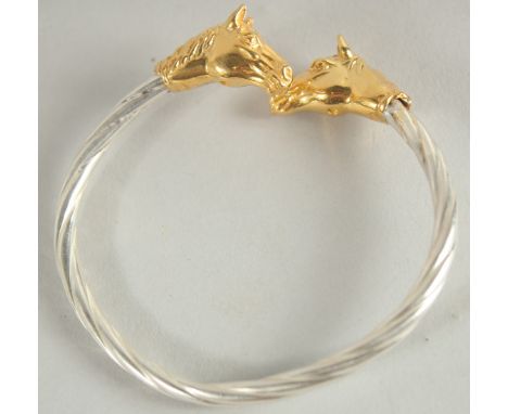 A STERLING SILVER TWISTED BANGLE with gilded horse head terminals.