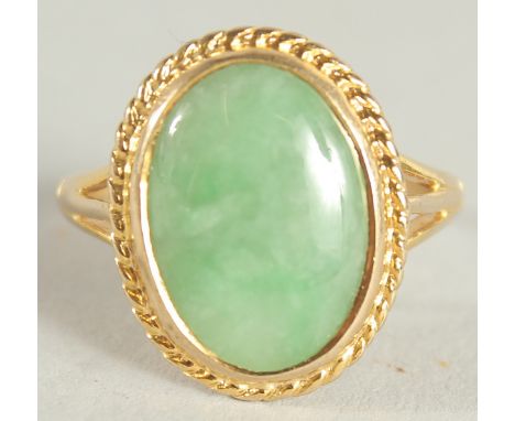 A YELLOW GOLD JADE OVAL RING.