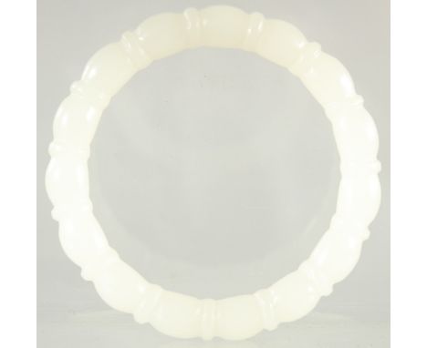 A CARVED WHITE JADE BANGLE. 3.25ins diameter.