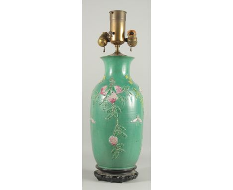 A CHINESE GREEN GROUND PORCELAIN LAMP on a wooden stand. 16ins high.