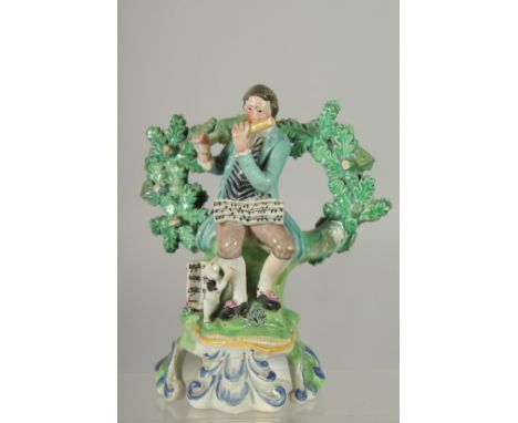 A PRATT WARE BOCAGE GROUP OF A SEATED MAN dog at his side playing a flute. 6ins high.