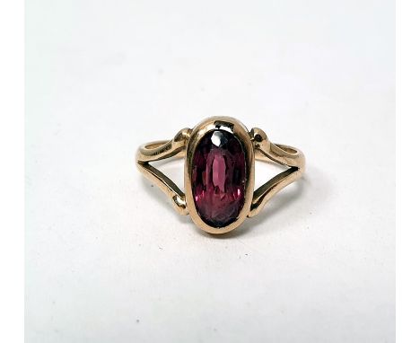 Gold ring set with a central oval garnet, with split shoulders (unmarked) (with damage)