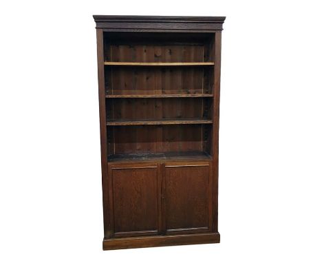 Old oak open bookcase with straight moulded cornice, adjustable shelves, cupboard below enclosing shelf, raised on plinth bas