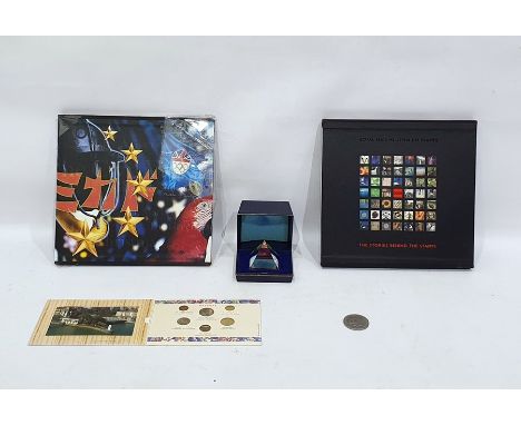 Two commemorative royal mail stamp albums, a small collection of coins and a paperweight inset with stamp