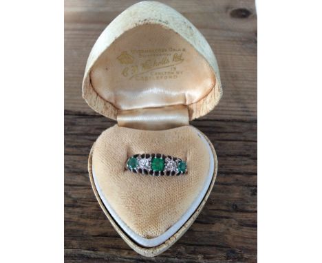 An 18ct white gold dress ring with 3 cushion cut emeralds and 2 diamonds size I