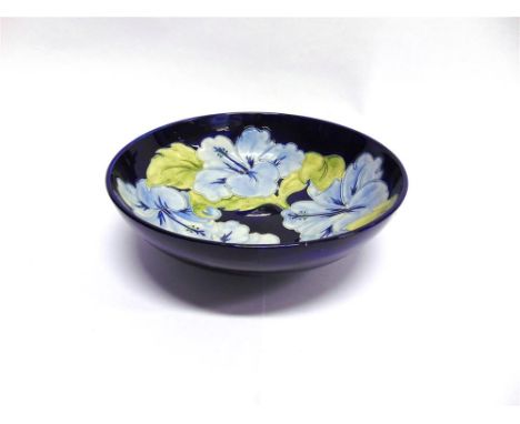 A LARGE MOORCROFT POTTERY BOWL  painted in light blue 'Hibiscus' pattern on a dark blue ground, impressed marks and painted m