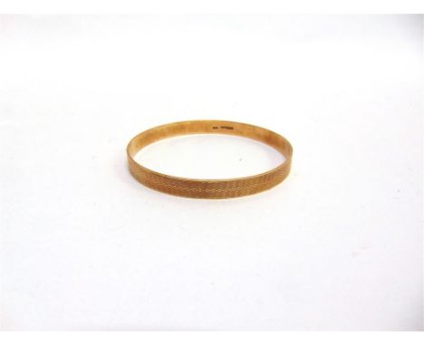 A 9 CARAT GOLD STIFF BANGLE Birmingham 1925, engine turned decoration, 8.1mm wide, 7.3cm internal diameter, 23.9g gross