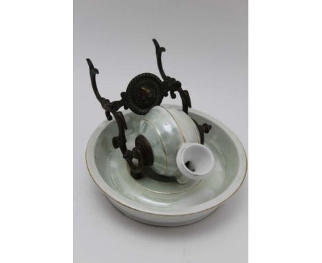 A French ceramic inkwell, snail form reservoir, rotates on a brass frame doubling as a pen stand on an almond green glazed bo