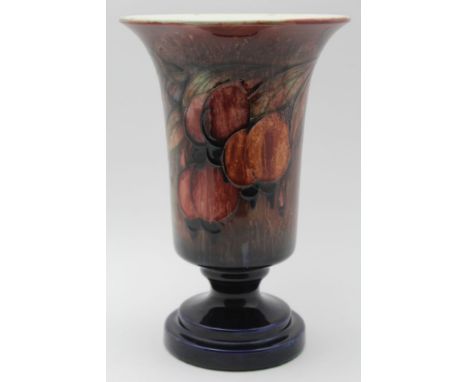 A William Moorcroft pottery vase, with flared rim on circular platform foot, tube lined wisteria design, glazed in reds, fadi