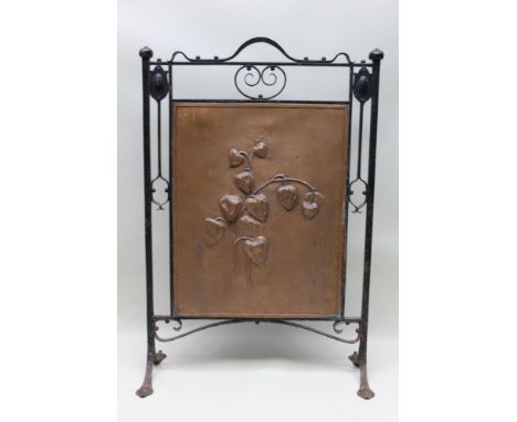 An Art Nouveau fire screen having a floral repousse decorated central copper panel, held within an ironwork frame, 73cm to to
