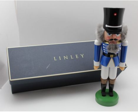 David Linley, a carved and painted wood nutcracker in the form of a soldier in a blue tunic, tall black hat, standing on circ