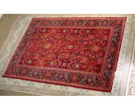 A first quarter 20th century red ground Iranian woven woollen floor rug, stylised geometric centrefield and floral guard bord