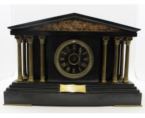 A late 19th century French black slate mantel clock of Architectural form, the classical pediment inset with a copper relief 