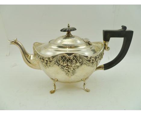 HENRY MATTHEWS A LATE VICTORIAN SILVER TEAPOT having repousse floral decoration, ebonised handle and knop, on four supports, 