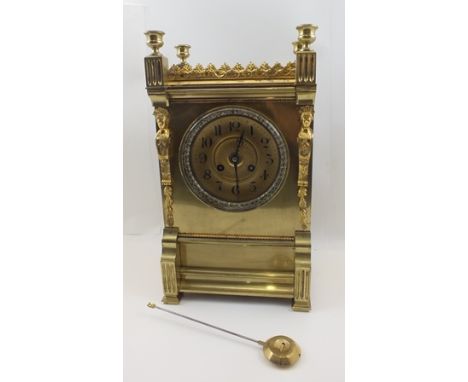 A 19TH CENTURY EMPIRE DESIGN GILT BRASS MANTEL CLOCK, architectural urn finials with floral crest over a front flanked by cas