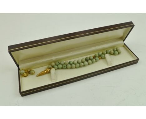 A JADE BEAD NECKLACE with yellow metal mounts, in vendor's box 