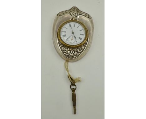 DOUGLAS CLOCK CO. AN EDWARDIAN SILVER CASED DESK CLOCK, having floral embossed shield form case, easel stand, a white enamel 