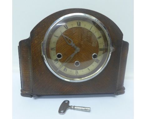 An oak mantel clock with chiming movement and key