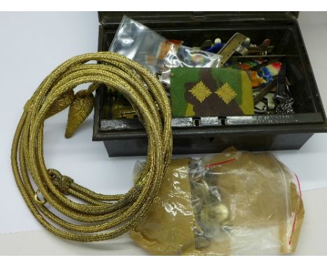 A tin of military badges, buttons and shoulder sash